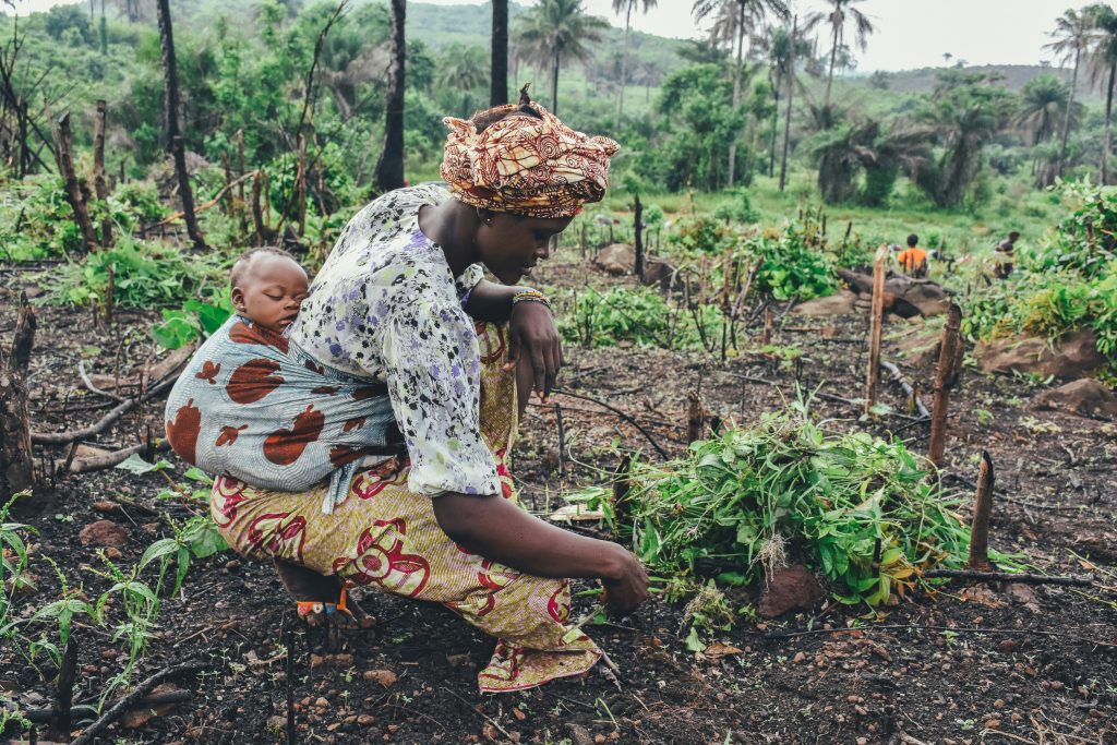 A woman kneels down near some plants | Wild Africa.
